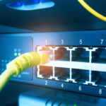 Network switch and ethernet cable in the rack cabinet background. Network communication concept. Blue tone.